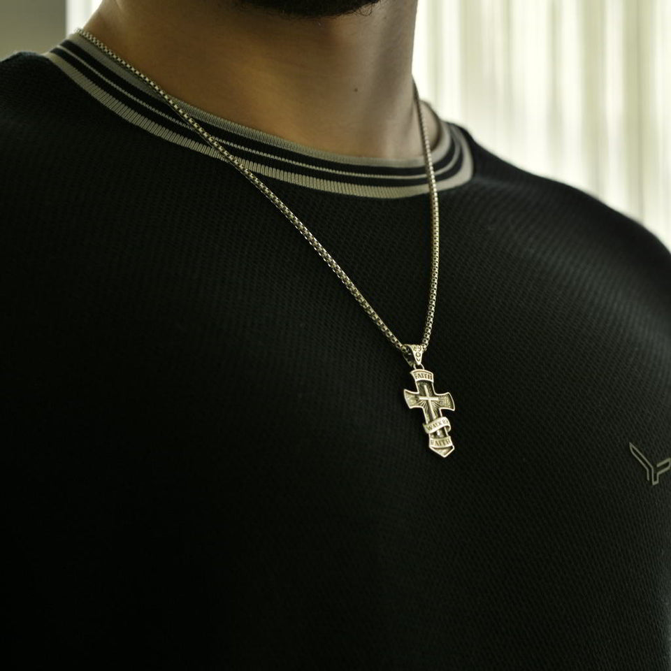 Handmade sterling silver faith necklace for men, Walk by Faith engraved. Person wearing a black sweater with a silver cross pendant necklace.