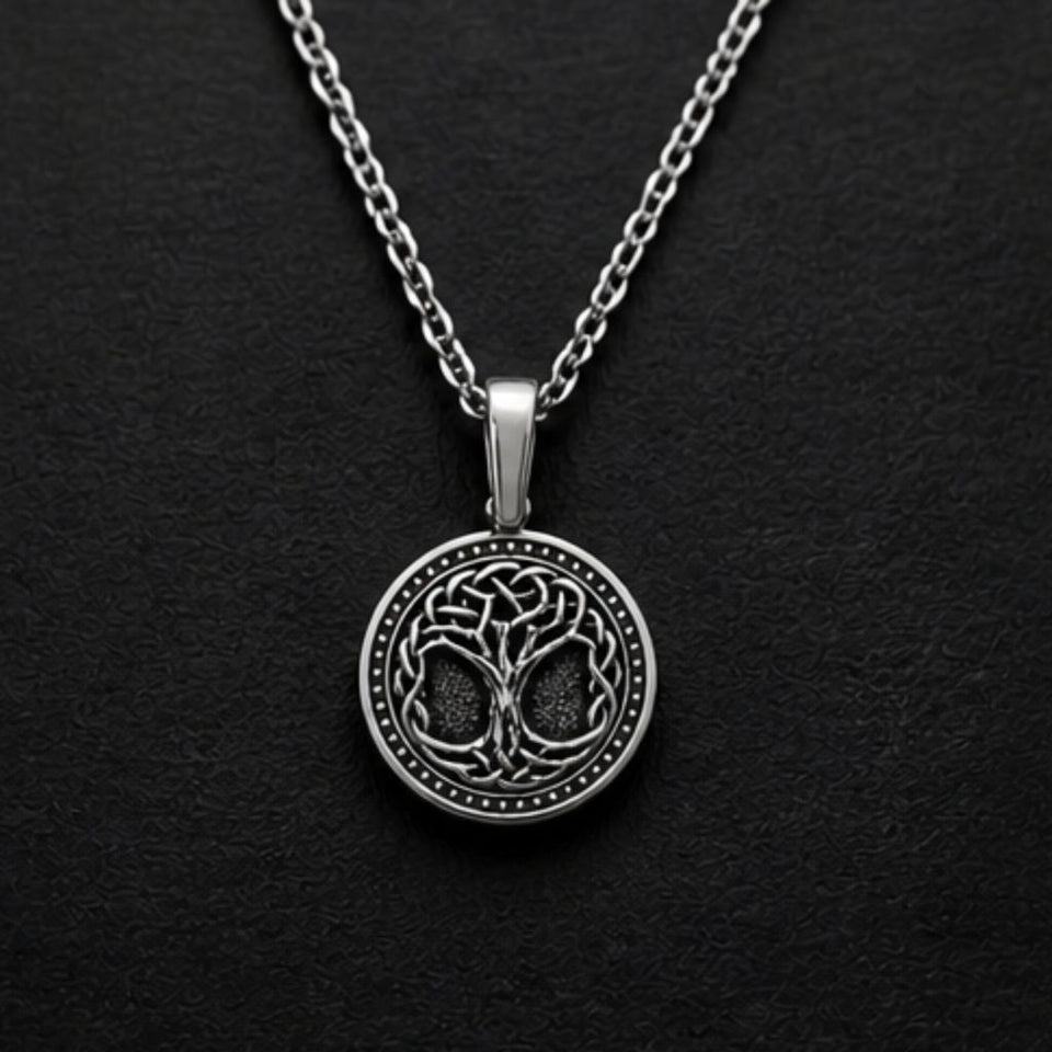 A silver pendant necklace featuring a circular tree of life design with Celtic knot details, displayed on a textured black background.