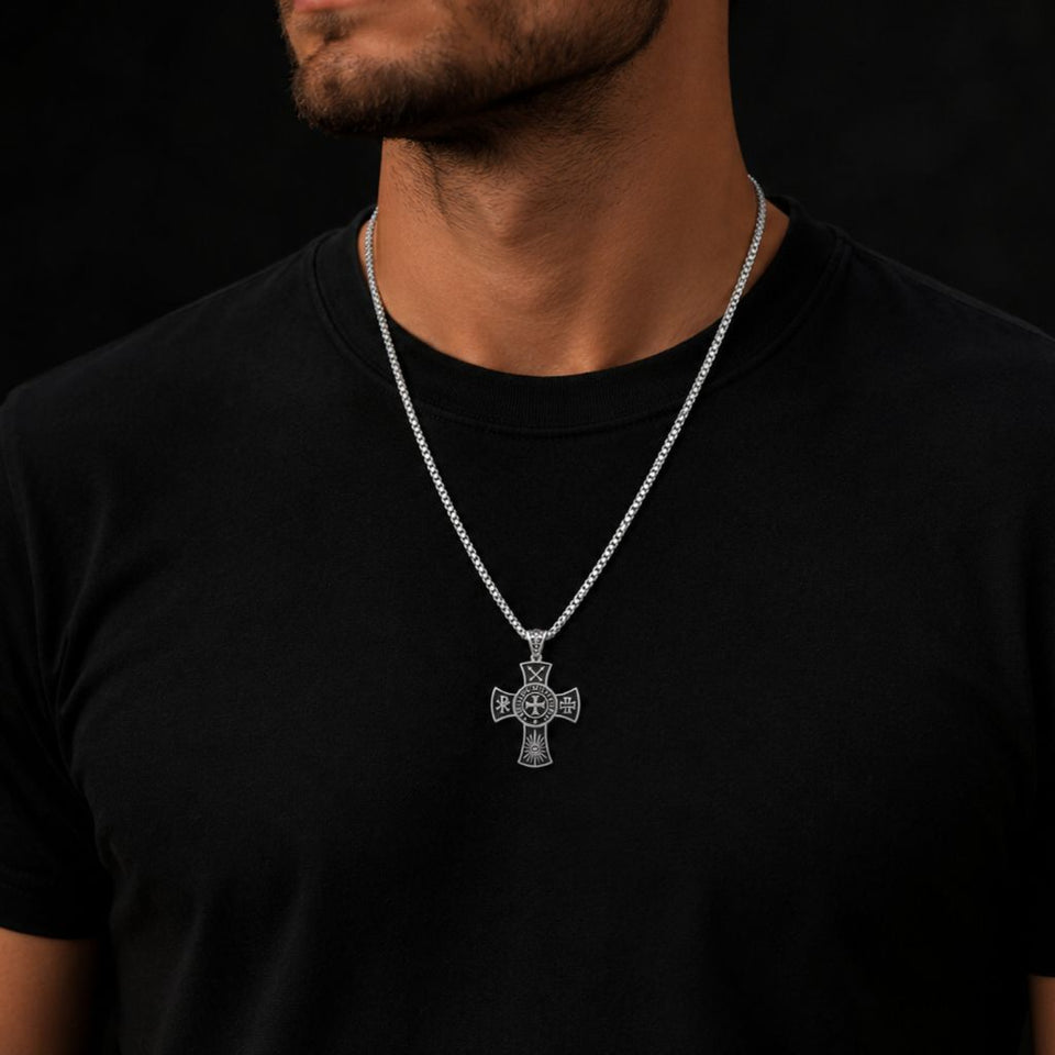 Man wearing a black t-shirt with a silver cross necklace against a dark background