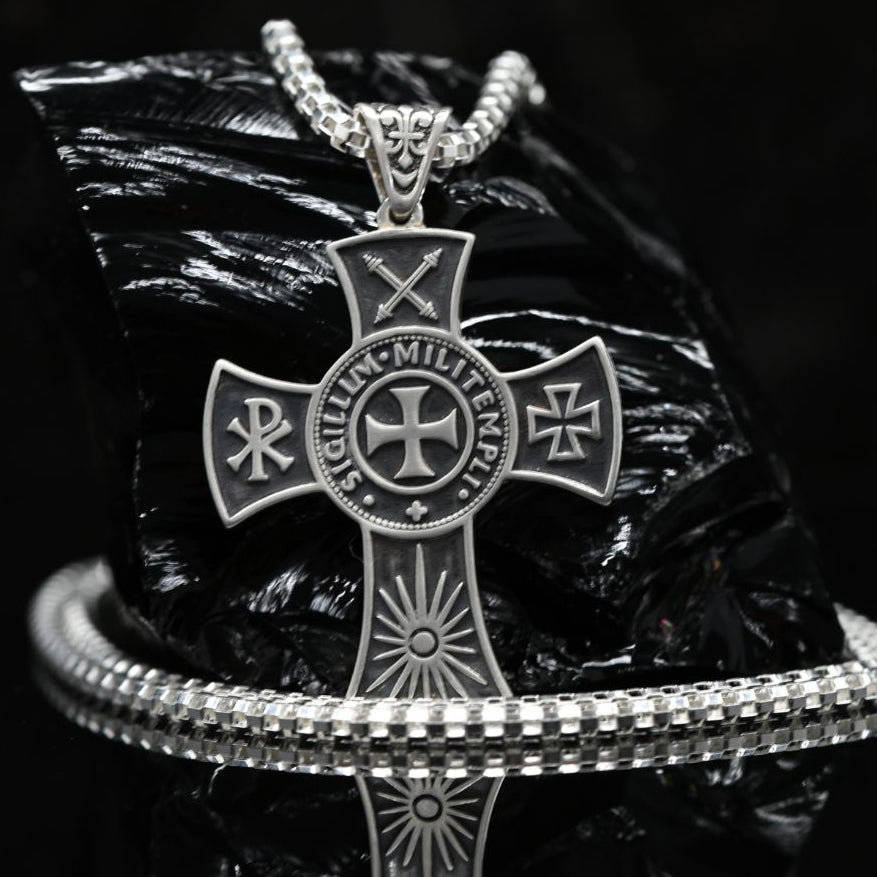 Handcrafted 925 sterling silver medieval cross necklace for men. A silver-toned metal cross pendant necklace with religious symbols and the words 'LIGHT MIGHTY CROSS' on the center, displayed on a black reflective surface with a matching chain and bracelet.