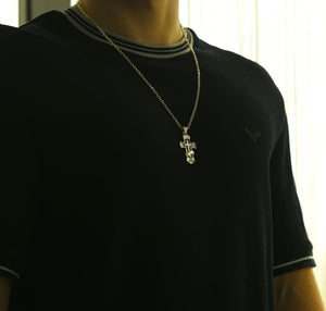 Model wearing a black t-shirt with a silver necklace featuring a cross pendant.