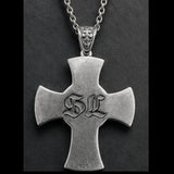 Silver cross pendant with 'SL' initials on a dark background