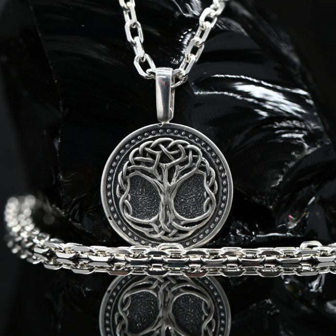 Silver Tree of Life pendant paired with 3mm sterling silver anchor chain. A 925 sterling silver tree of life pendant necklace with a matching chain and bracelet, displayed on a glossy black reflective surface.