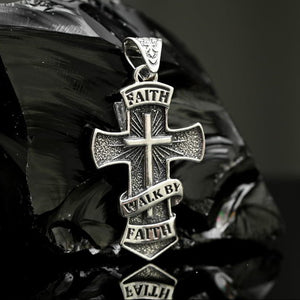 Silver cross pendant Faith with engraved text on a reflective surface