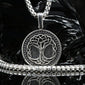 A 925 sterling silver necklace with a three of life pendant featuring a tree of life design, displayed on a black reflective surface with a black rock prop.